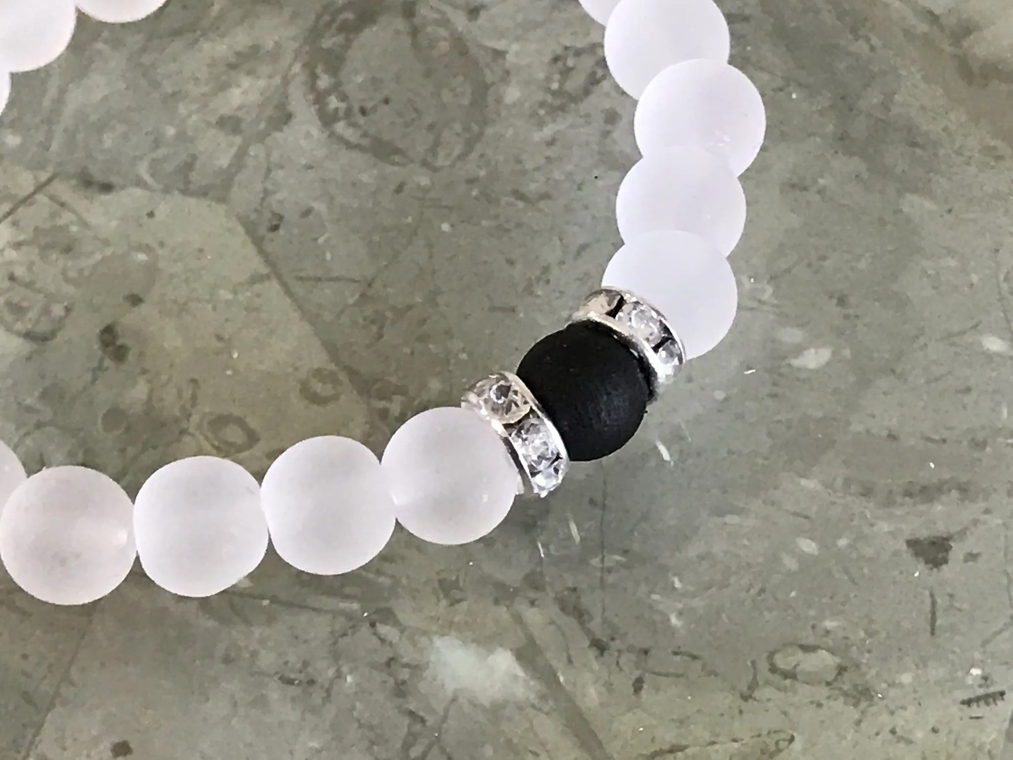 White frosted glass beads with a black beads and two rhinestone beads